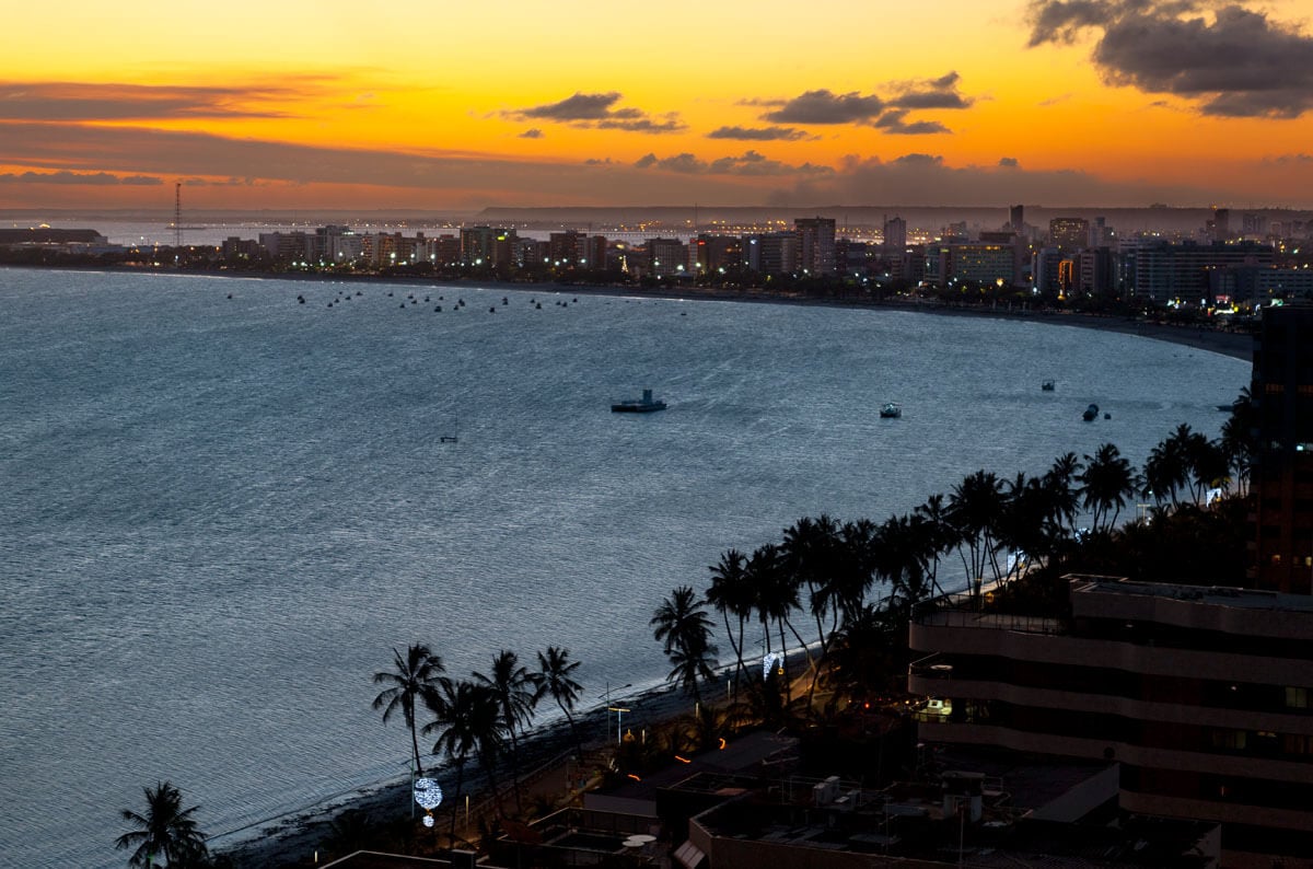 Vista aérea da Praia de Ponta Verde com céu nublado durante o pôr do sol.